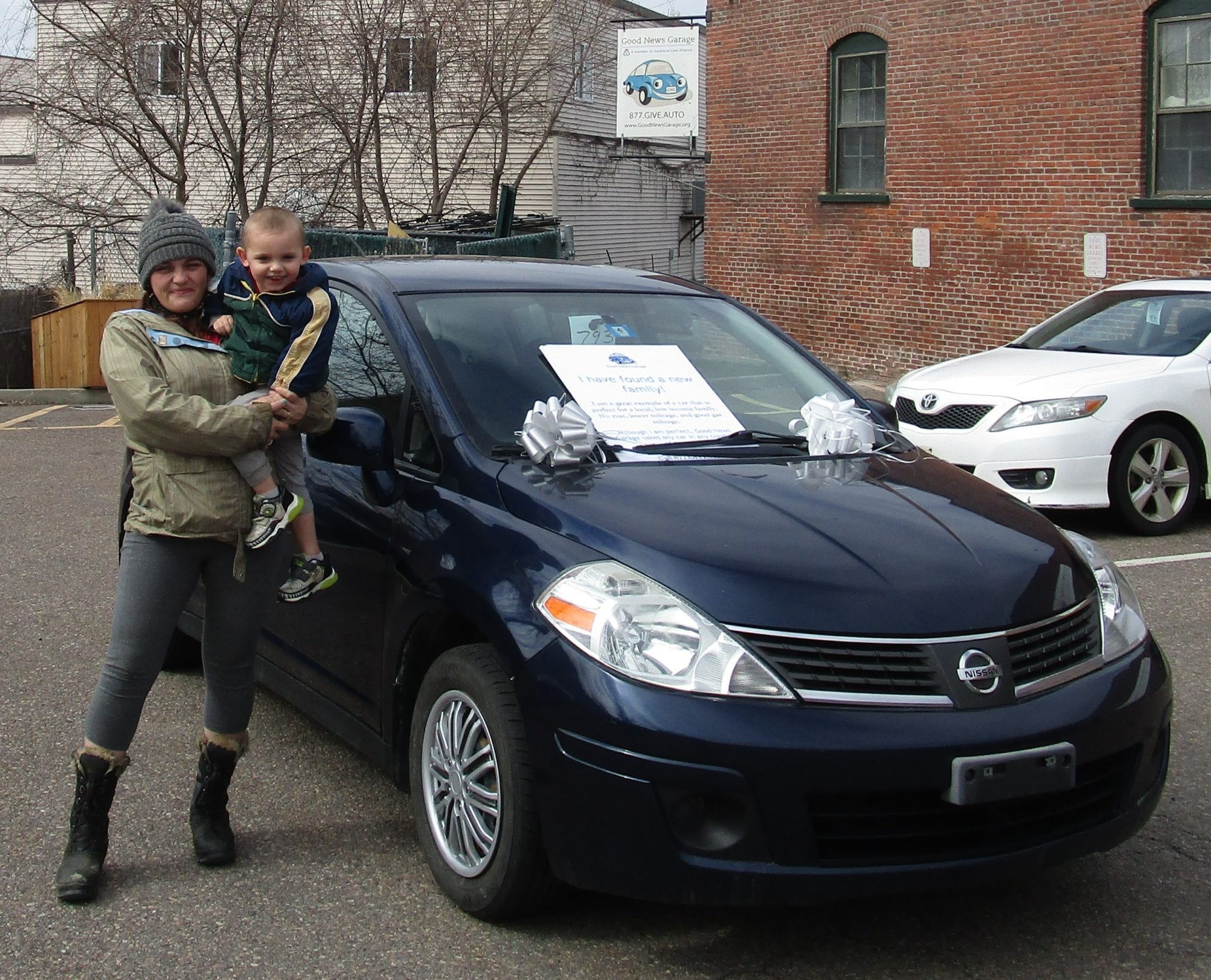 Megan and her son stand in front of the donated car they received from Good News Garage