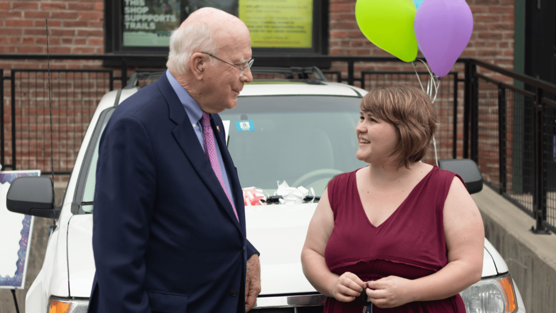 Vermont Senator Patrick Leahy speaks with the recipioent of Good News Garage's 5,500th donated car, MErcedeze Moore.