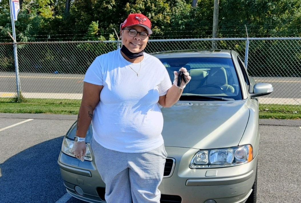 Mykilah from Massachusetts poses for a photo next to the donated car she received from Good News Garage.