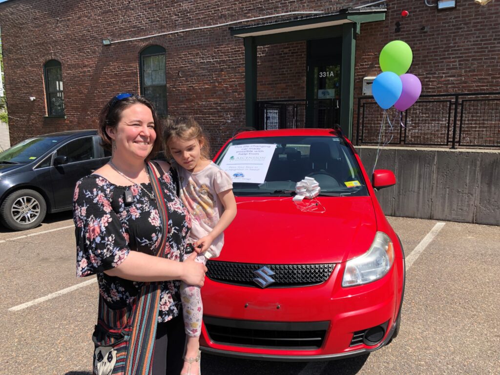 Car recipient, Tanya, stands in front of her donated Suzuki with her daughter.