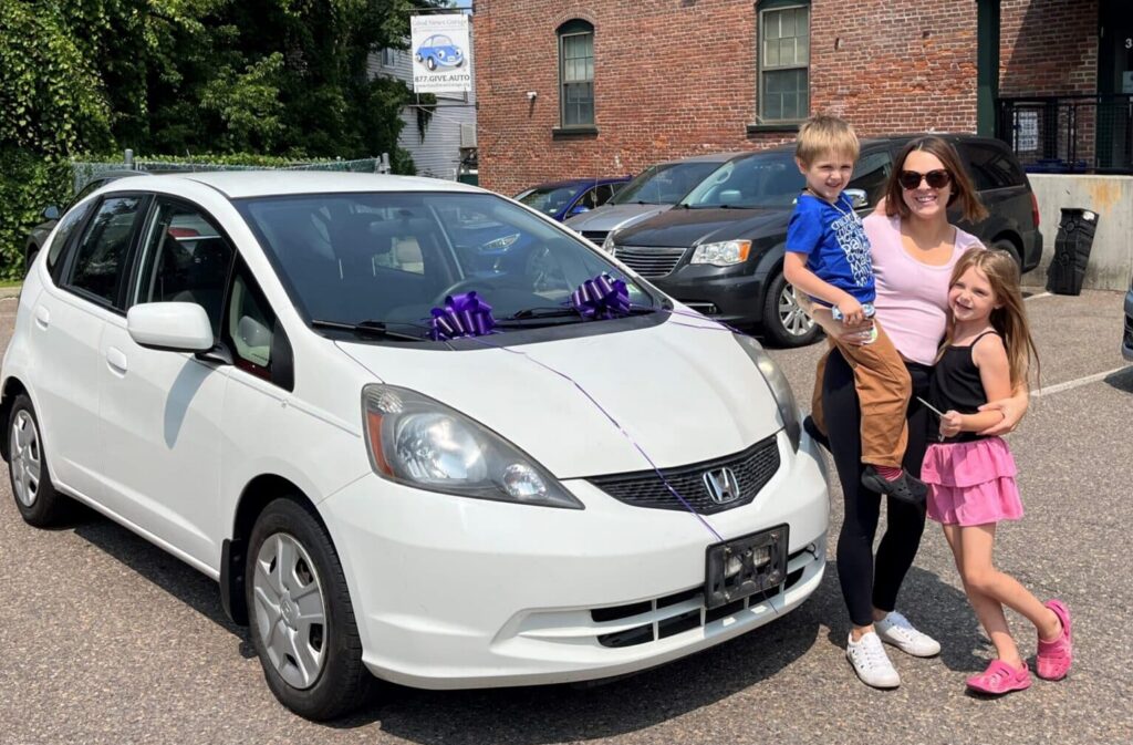 A family stands next to the donated car they received from Good News Garage.