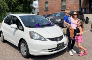 A family stands next to the donated car they were given by Good News Garage